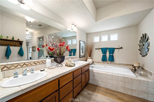 10204 Mount Olympus Valley Rd, Fallbrook, CA 92028 - bathroom featuring a garden tub, double vanity, and wood finished floors