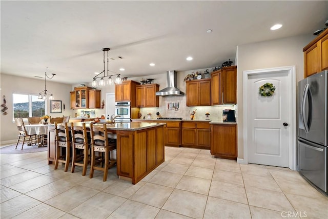 10204 Mount Olympus Valley Rd, Fallbrook, CA 92028 - kitchen featuring stainless steel appliances, wall chimney range hood, brown cabinets, light tile patterned floors, and recessed lighting