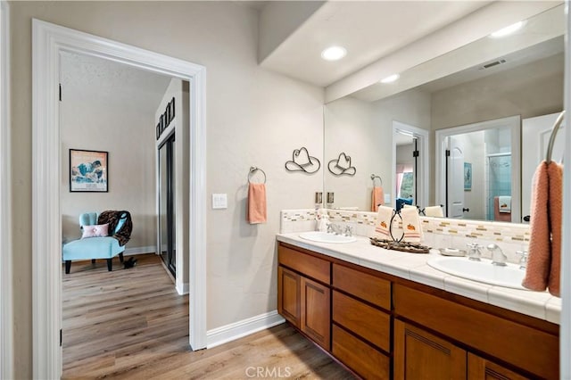 10204 Mount Olympus Valley Rd, Fallbrook, CA 92028 - bathroom with double vanity, wood finished floors, tasteful backsplash, and a shower with door