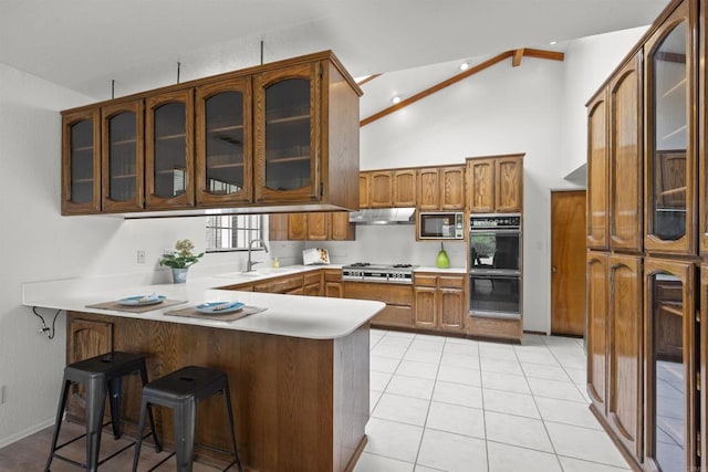 2125 Prospect St, National City, CA 91950 - kitchen featuring a peninsula, stainless steel gas stovetop, under cabinet range hood, brown cabinetry, and high vaulted ceiling