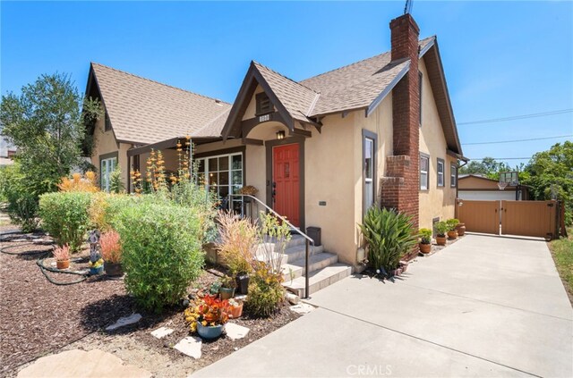 1260 Sinaloa Ave, Pasadena, CA 91104 - tudor-style house featuring a gate, stucco siding, roof with shingles, and a chimney