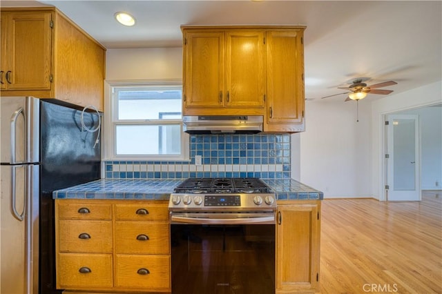 273 Almond St, San Luis Obispo, CA 93405 - kitchen featuring stainless steel appliances, under cabinet range hood, decorative backsplash, a ceiling fan, and brown cabinets