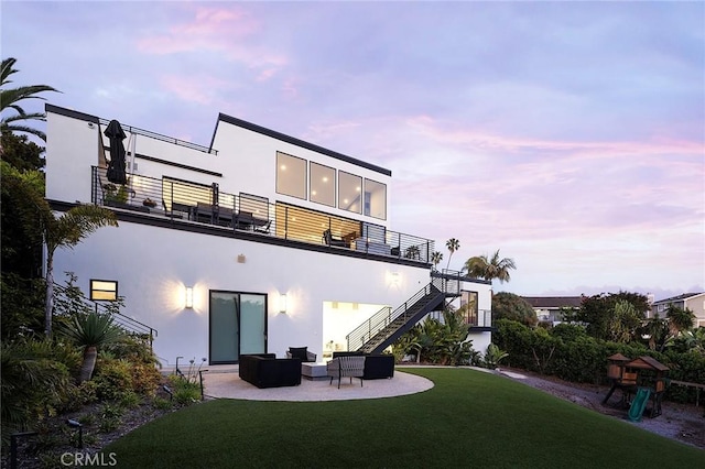 152 El Levante, San Clemente, CA 92672 - back of house at dusk with a balcony, an outdoor hangout area, a patio area, stucco siding, and a yard