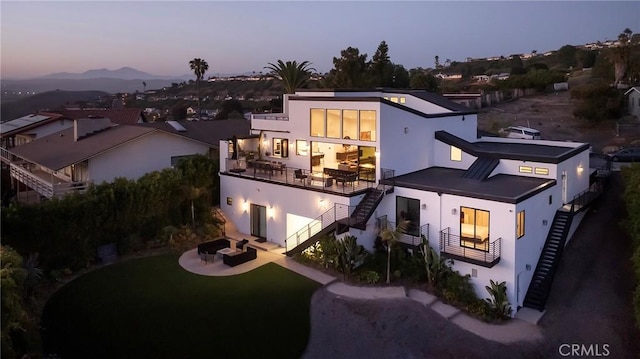152 El Levante, San Clemente, CA 92672 - back of house at dusk featuring stairway, a balcony, stucco siding, and a patio