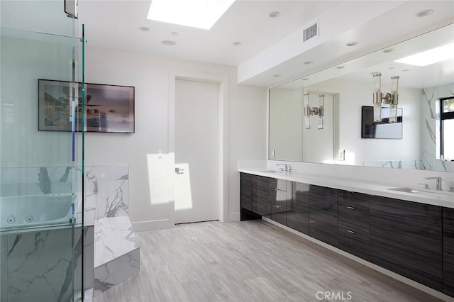 152 El Levante, San Clemente, CA 92672 - bathroom featuring a skylight, double vanity, wood finished floors, a marble finish shower, and recessed lighting