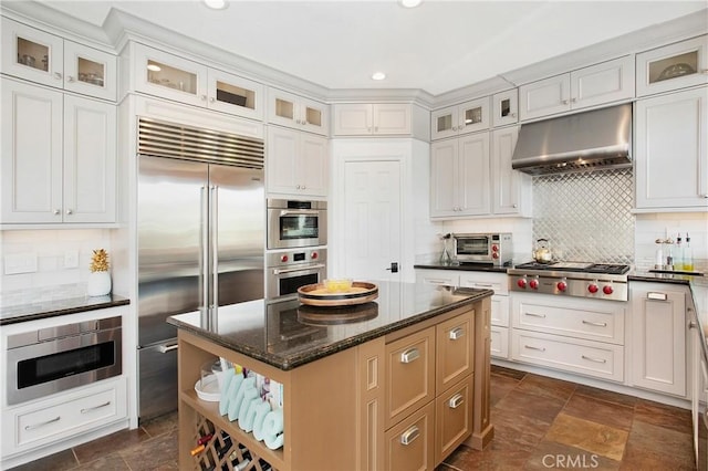 4 Sunswept Mesa, Aliso Viejo, CA 92656 - kitchen featuring under cabinet range hood, built in appliances, a center island, backsplash, and dark stone counters
