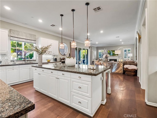 22385 Midtown Ct, Saugus, CA 91350 - kitchen featuring a center island, crown molding, decorative backsplash, open floor plan, and dark wood finished floors