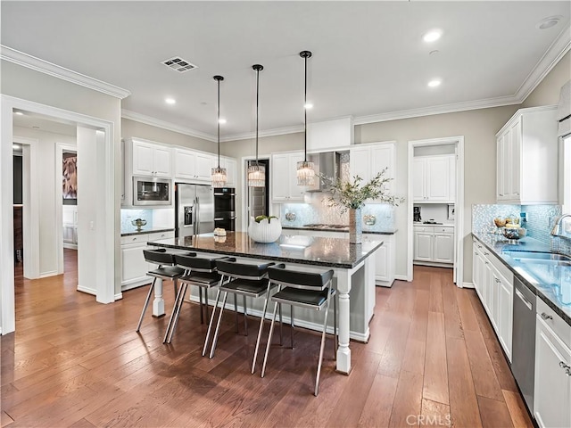 22385 Midtown Ct, Saugus, CA 91350 - kitchen with stainless steel appliances, a sink, a breakfast bar, tasteful backsplash, and white cabinets