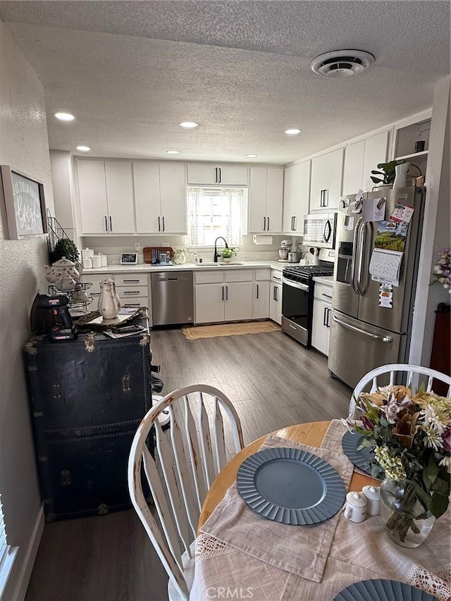 37098 San Bruno Ave, Barstow, CA 92311 - kitchen featuring appliances with stainless steel finishes, a sink, light wood-type flooring, a textured ceiling, and light countertops