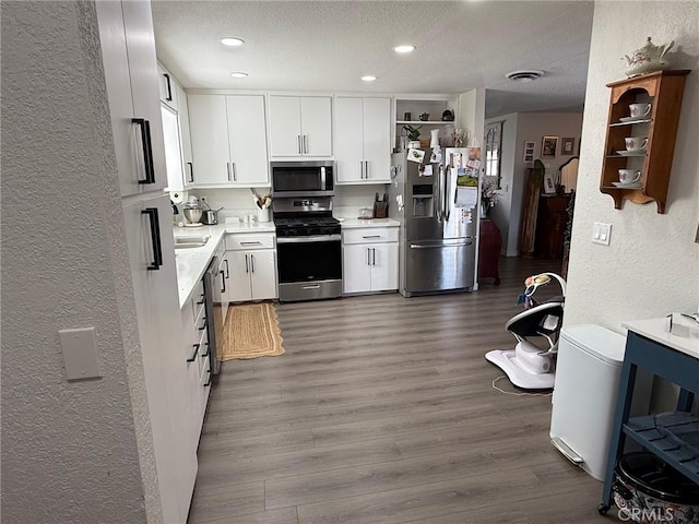 37098 San Bruno Ave, Barstow, CA 92311 - kitchen with appliances with stainless steel finishes, a textured wall, open shelves, a textured ceiling, and light countertops