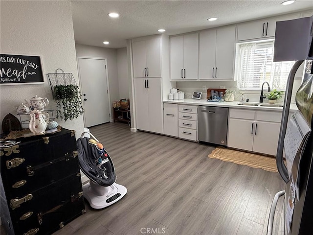 37098 San Bruno Ave, Barstow, CA 92311 - kitchen with stainless steel dishwasher, a sink, refrigerator with ice dispenser, light wood-style flooring, and white cabinetry