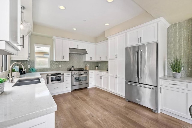 295 Chinquapin Ave, Carlsbad, CA 92008 - kitchen with premium appliances, a sink, under cabinet range hood, white cabinetry, and light wood-style flooring