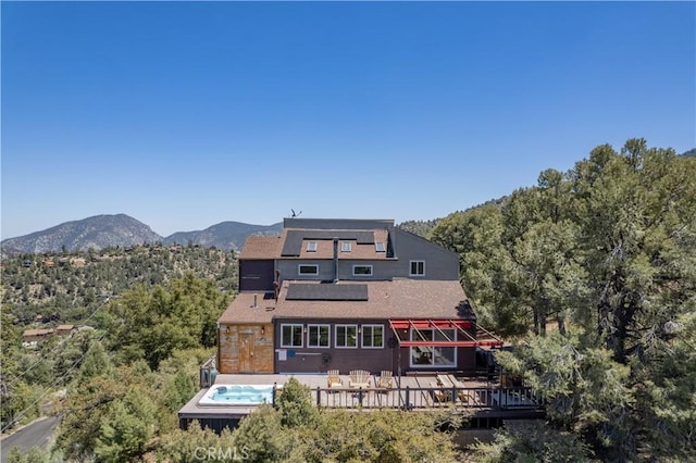 1903 Dusk Pl, Pine Mountain Club, CA 93225 - rear view of house with roof mounted solar panels, a deck with mountain view, a wooded view, outdoor dining area, and a hot tub