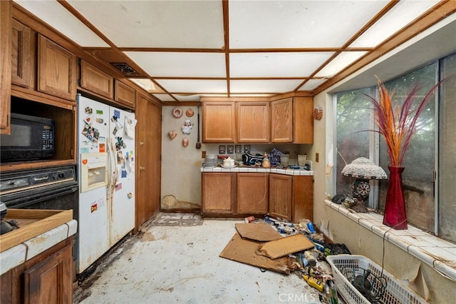 13397 Robin Ct, Yucaipa, CA 92399 - kitchen featuring black microwave, white fridge with ice dispenser, tile counters, brown cabinets, and unfinished concrete floors