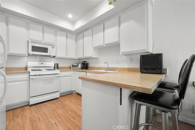 10831 Roycroft St Unit 8, Sun Valley, CA 91352 - kitchen with white appliances, a sink, a peninsula, white cabinetry, and light wood finished floors