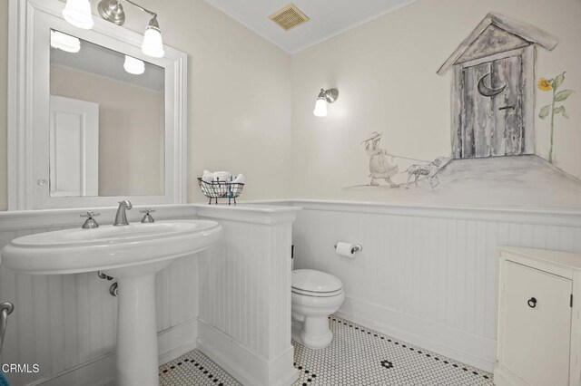 4177 Ocean Dr, Oxnard, CA 93035 - bathroom with a wainscoted wall, toilet, a sink, tile patterned flooring, and a decorative wall