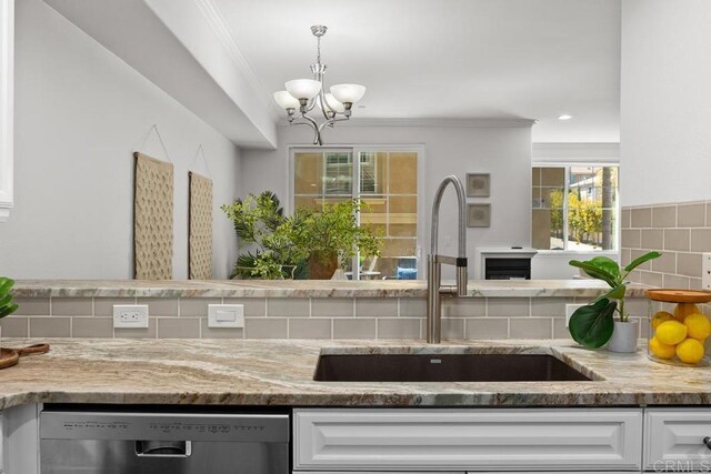 2778 Carlsbad Blvd Unit 201, Carlsbad, CA 92008 - kitchen with stainless steel dishwasher, a sink, backsplash, white cabinetry, and crown molding