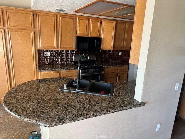1715 Lake Way, Lancaster, CA 93534 - kitchen featuring stainless steel gas stove, black microwave, decorative backsplash, brown cabinets, and a peninsula