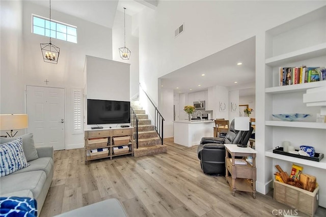 2693 Lookout Cir, Chino Hills, CA 91709 - living area featuring a high ceiling, light wood-type flooring, stairs, a chandelier, and built in shelves