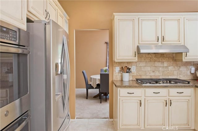 22447 Poplar St, Saugus, CA 91390 - kitchen featuring stainless steel appliances, cream cabinetry, under cabinet range hood, backsplash, and light colored carpet