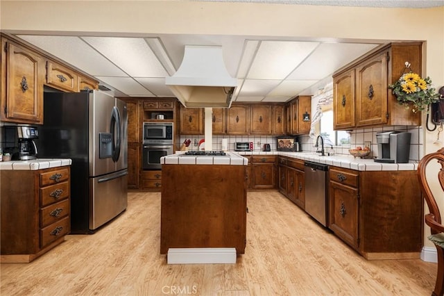 3298 N Zediker Ave, Sanger, CA 93657 - kitchen with appliances with stainless steel finishes, tile countertops, premium range hood, light wood finished floors, and a kitchen island