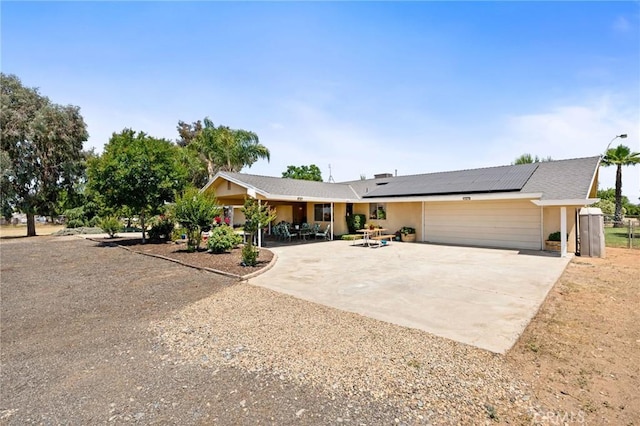 3298 N Zediker Ave, Sanger, CA 93657 - view of front of house featuring driveway, a garage, solar panels, stucco siding, and a patio area