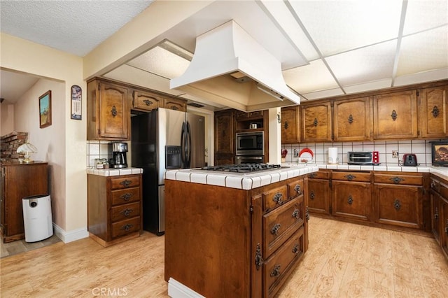 3298 N Zediker Ave, Sanger, CA 93657 - kitchen featuring island range hood, light wood-style flooring, appliances with stainless steel finishes, and backsplash