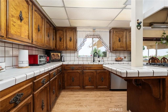 3298 N Zediker Ave, Sanger, CA 93657 - kitchen with a sink, light wood-style floors, decorative backsplash, a drop ceiling, and brown cabinets