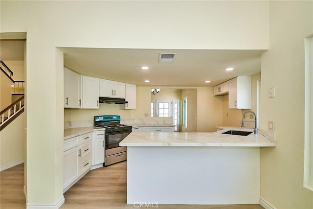 13855 Calada Dr, Moreno Valley, CA 92553 - kitchen with gas range, a peninsula, a sink, under cabinet range hood, and light stone counters