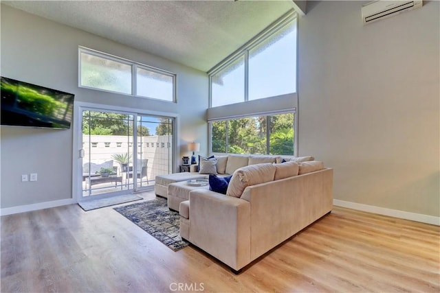 259 Calle Aragon Unit A, Laguna Woods, CA 92637 - living room with a wall mounted AC, wood finished floors, baseboards, a towering ceiling, and a textured ceiling