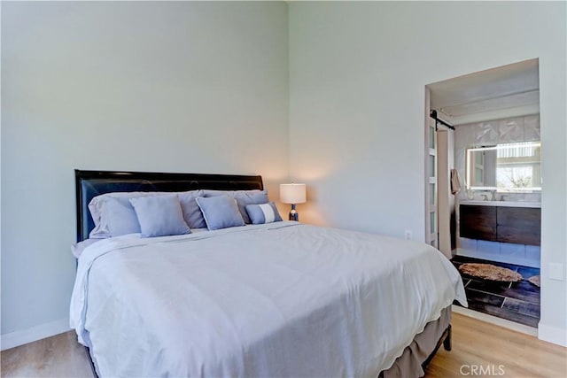 259 Calle Aragon Unit A, Laguna Woods, CA 92637 - bedroom with light wood-type flooring, baseboards, and connected bathroom