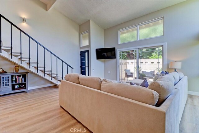 259 Calle Aragon Unit A, Laguna Woods, CA 92637 - living area featuring a high ceiling, stairs, light wood-style flooring, and baseboards