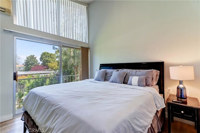 259 Calle Aragon Unit A, Laguna Woods, CA 92637 - bedroom featuring access to exterior, a towering ceiling, an AC wall unit, and wood finished floors