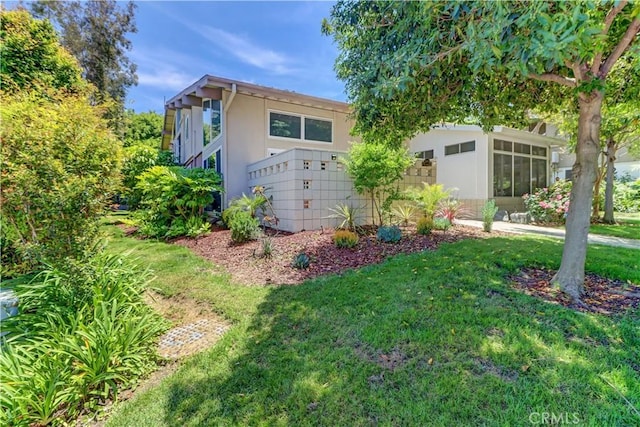 259 Calle Aragon Unit A, Laguna Woods, CA 92637 - view of front facade featuring a front yard, a sunroom, and stucco siding