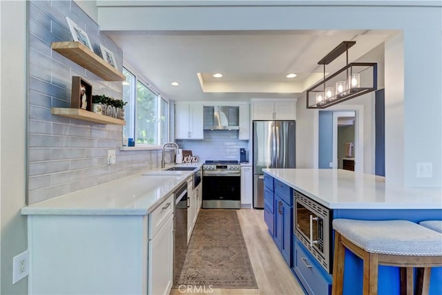 259 Calle Aragon Unit A, Laguna Woods, CA 92637 - kitchen featuring appliances with stainless steel finishes, open shelves, blue cabinetry, wall chimney range hood, and white cabinetry
