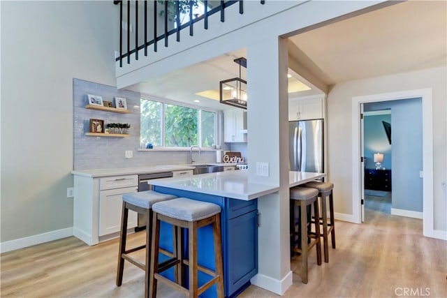 259 Calle Aragon Unit A, Laguna Woods, CA 92637 - kitchen with freestanding refrigerator, a breakfast bar area, white cabinetry, and light countertops