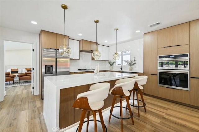 4816 Saint Andrews Ave, Buena Park, CA 90621 - kitchen with appliances with stainless steel finishes, light wood finished floors, a breakfast bar, light countertops, and recessed lighting