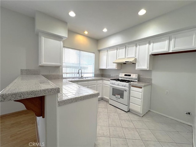 1729 Sunflower Ave Unit A, Glendora, CA 91740 - kitchen with white gas range oven, under cabinet range hood, a peninsula, a sink, and white cabinets