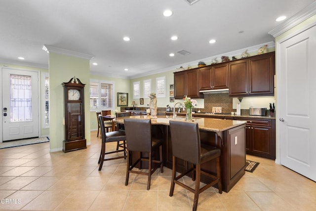 4003 Galapagos Way, Oxnard, CA 93035 - kitchen with crown molding, a kitchen breakfast bar, recessed lighting, a center island with sink, and light tile patterned floors