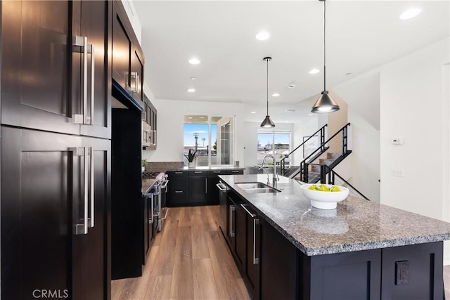 645 Channel Way, Costa Mesa, CA 92627 - kitchen featuring light wood finished floors, a sink, an island with sink, appliances with stainless steel finishes, and dark stone counters