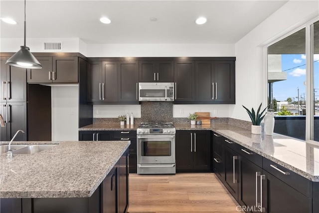 645 Channel Way, Costa Mesa, CA 92627 - kitchen with appliances with stainless steel finishes, a sink, hanging light fixtures, light stone countertops, and light wood-style floors