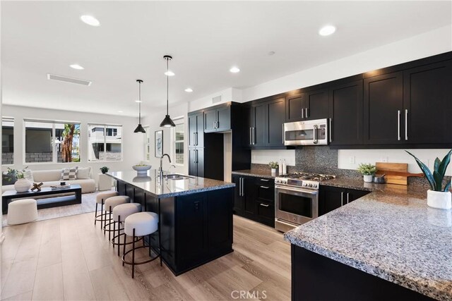 645 Channel Way, Costa Mesa, CA 92627 - kitchen with appliances with stainless steel finishes, a sink, open floor plan, light stone countertops, and dark cabinets
