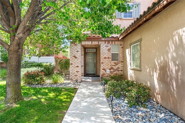 35509 Trevino Trl, Beaumont, CA 92223 - property entrance with stucco siding, brick siding, a tiled roof, and a lawn