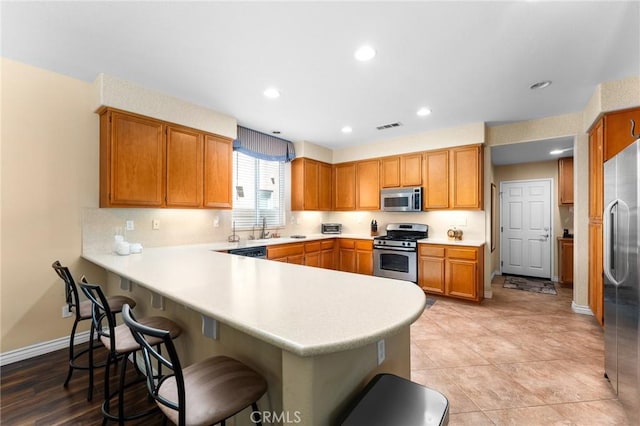 35509 Trevino Trl, Beaumont, CA 92223 - kitchen with stainless steel appliances, a peninsula, light countertops, baseboards, and a breakfast bar