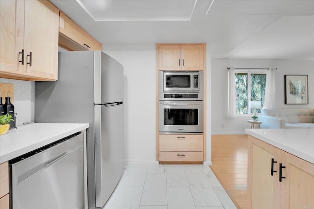 7077 Camino Pacheco, San Diego, CA 92111 - kitchen featuring light brown cabinetry, appliances with stainless steel finishes, light countertops, open floor plan, and baseboards