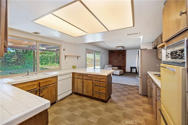 6164 Amberwood Dr, Rancho Cucamonga, CA 91701 - kitchen featuring dishwasher, open floor plan, brown cabinetry, a peninsula, and freestanding refrigerator