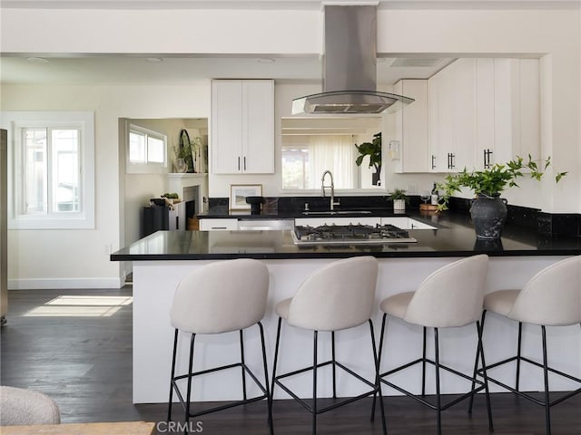 5512 W 117th St, Hawthorne, CA 90304 - kitchen featuring island range hood, stainless steel appliances, white cabinets, dark countertops, and a peninsula