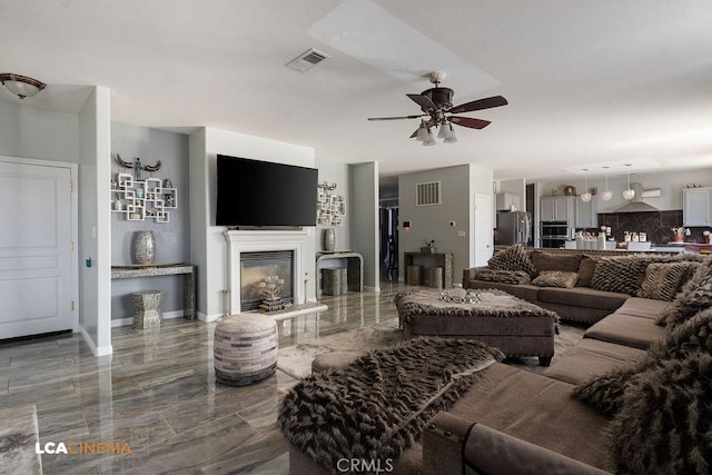 11703 Revolution Rd, Bakersfield, CA 93312 - living room with ceiling fan, marble tiled flooring, a glass covered fireplace, and baseboards