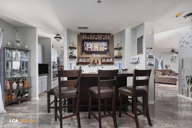 11703 Revolution Rd, Bakersfield, CA 93312 - indoor wet bar with marble tiled flooring, ceiling fan, and stainless steel double oven