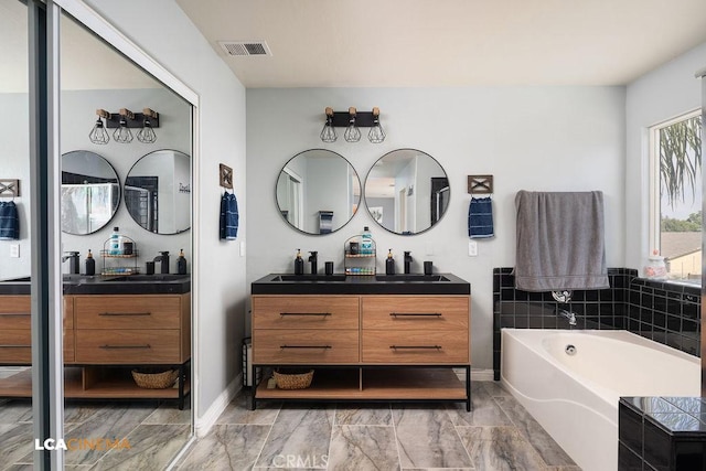 11703 Revolution Rd, Bakersfield, CA 93312 - bathroom featuring double vanity, a garden tub, marble finish floors, and baseboards